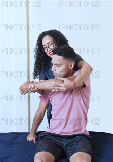 Portrait of female physiotherapist rehabilitating male patient arm. Muscle rehabilitation physiotherapy. Physiotherapist woman evaluating a patient's arm in the office