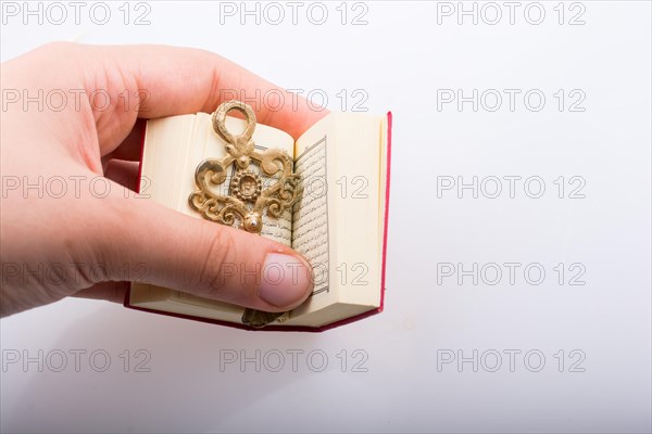 Hand holding Key and Islamic Holy Book Quran in mini size