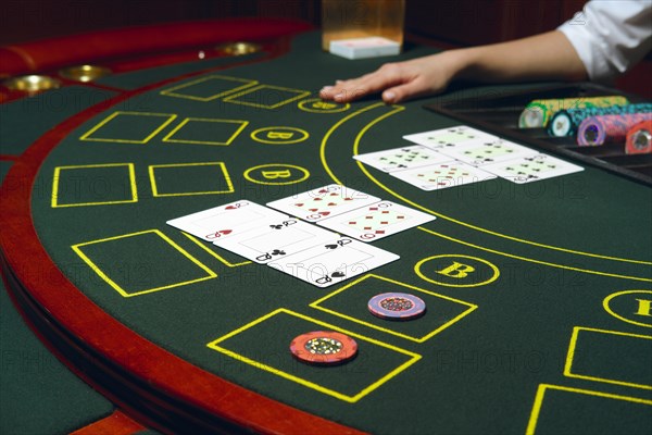 Casino black jack table with chips and cards. Winning combination. Hand of Croupier behind gambling table