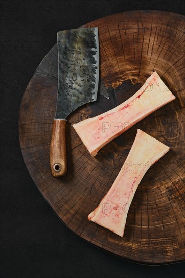 Overhead view of large beef bone marrow chopped on half on wooden stump