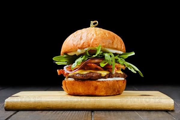 Tasty beef burger with bacon on wooden serving board