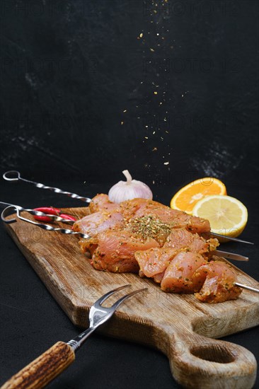 Pouring with sweet and spicy rub raw turkey meat on dark background