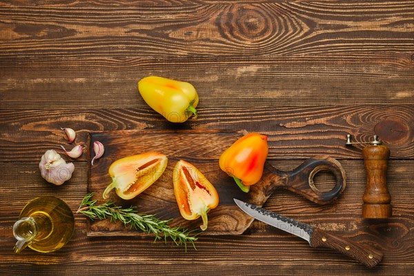 Sweet bell pepper or paprika cut on half and whole on wooden cutting board