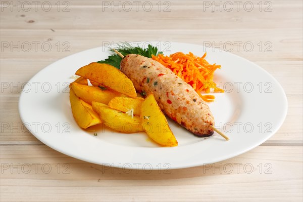 Kebab on skewer with fried potato and spicy carrot