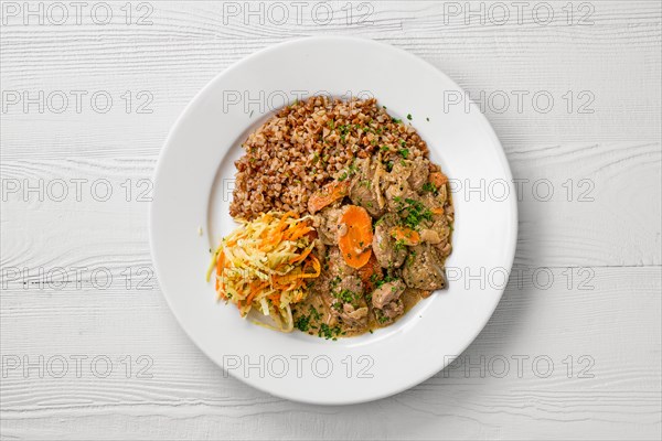 Top view of plate with chicken liver with buckwheat and pickled cabbage salad