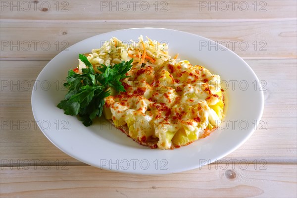 Chopped meat fillet with potato cubes covered with melted cheese and served with pickled cabbage and carrot