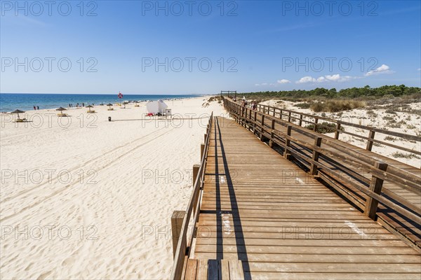 Wide sandy beach with wooden bridges along the dunes in Monte Gordo