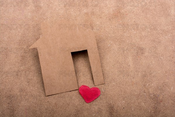 Little house shape cut out of paper and a heart on a canvas background