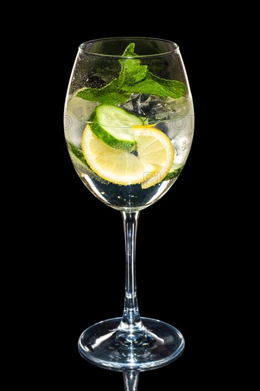 Cold Lemon and cucumber cocktail with a sparkling wine with ice cubes in wine glass isolated on black