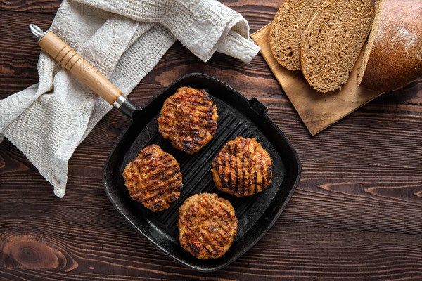 Top view of cast iron grill pan with beef cutlets and freshly baked brown bread