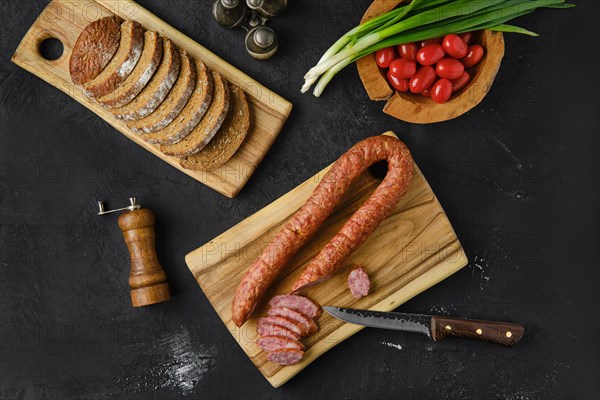 Overhead view of smoked lamb sausage rings on wooden cutting board on kitchen table