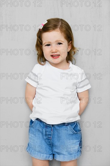 Two years old girl in white t-short and jeans shorts posing in studio