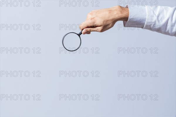 Hand holding magnifying glass on isolated background. Man's hand holding magnifying glass on white background. Hand holding magnifying glass looking for something with space for text