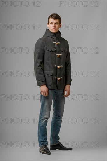 Full length portrait of handsome man in warm woolen coat posing in studio