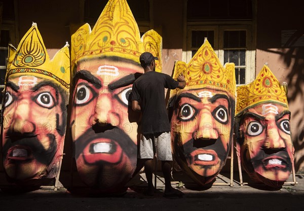 Artisan painting on a face of Ravana idol ahead of Dussehra Festival