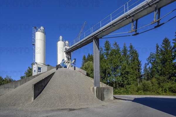 Steel silos and shovel crane with gravel piles and conveyor belt