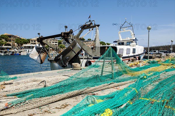 Fishing nets lying stretched out to dry for repair on quay at harbour pier