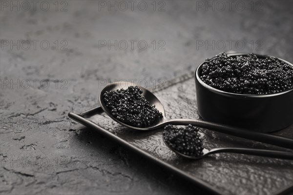 Black caviar bowl with spoons ladle