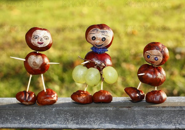 Three chestnut figures with grapes in the evening light