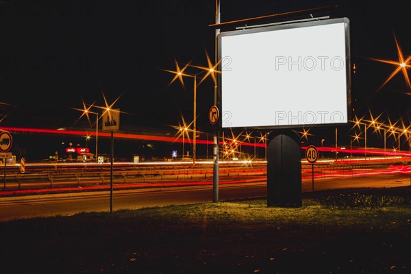 Blank advertisement billboard with blurred traffic lights night