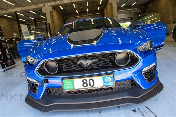 Front view of racing car sports car Ford Mustang Mach 1 standing with open doors in pit of race track