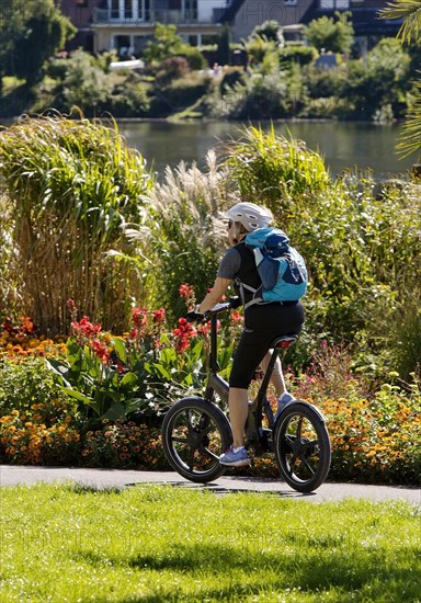 Bicycle rider on the Ruhr valley cycle path with lush vegetation at the reservoir