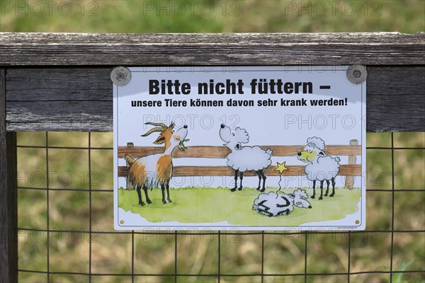 Sign for feeding ban in front of a goat and sheep meadow