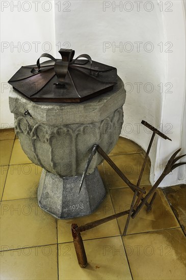 Baptismal font with antique agricultural implement