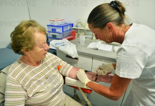 This internist in the centre of a larger city works mainly as a family doctor. The photo shows: Blood sampling by the doctor's assistant