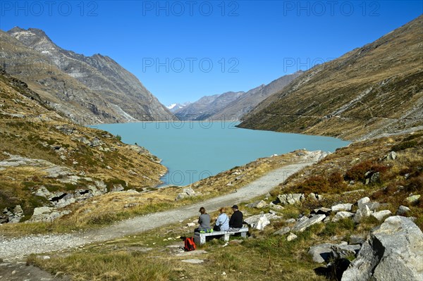 Three hikers resting at the Mattmark reservoir