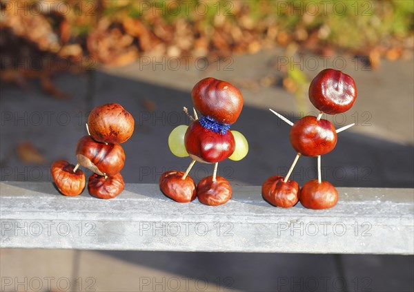 Three chestnut figures with grapes in the evening light