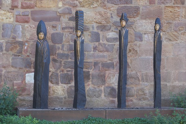 Four slender brown sculptures made of wood on the wall of the moated castle in Bad Vilbel