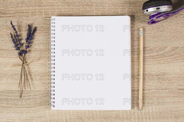 Blank spiral notebook pencil headphone lavender twigs wooden background