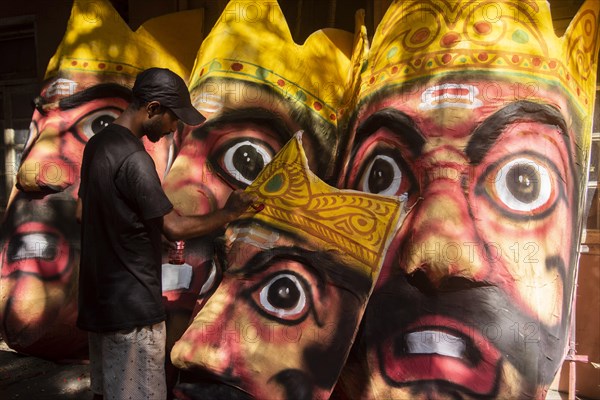 Artisan painting on a face of Ravana idol ahead of Dussehra Festival