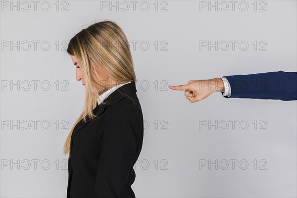 Businessman s hand blaming young businesswoman against grey backdrop