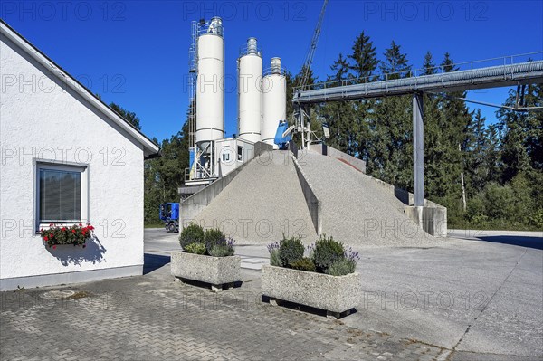 Steel silos and shovel crane with gravel piles and conveyor belt