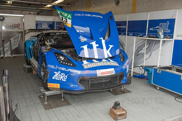 Corvette C7 GT3-R stands with open bonnet for maintenance adjustment on jack in pits at car race