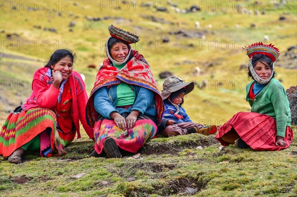 Quechua Indian family in traditional dress sitting in a meadow