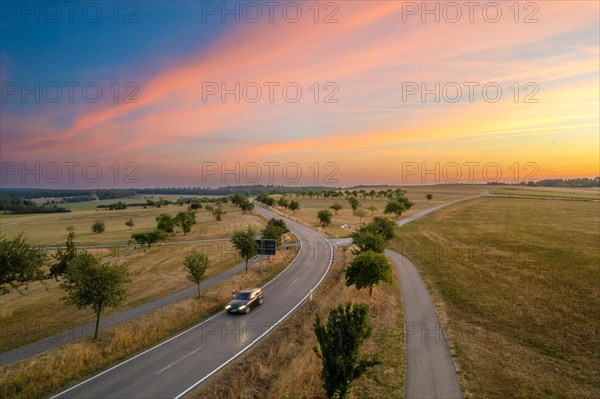Aerial view of a road and dried grass in midsummer at sunrise
