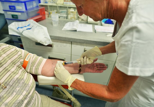 This internist in the centre of a larger city works mainly as a family doctor. The photo shows: Blood sampling by the doctor's assistant