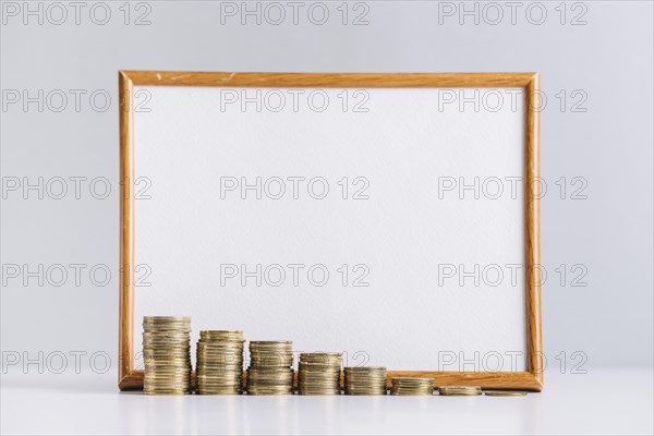 Increasing stacked coins front blank white board reflective desk