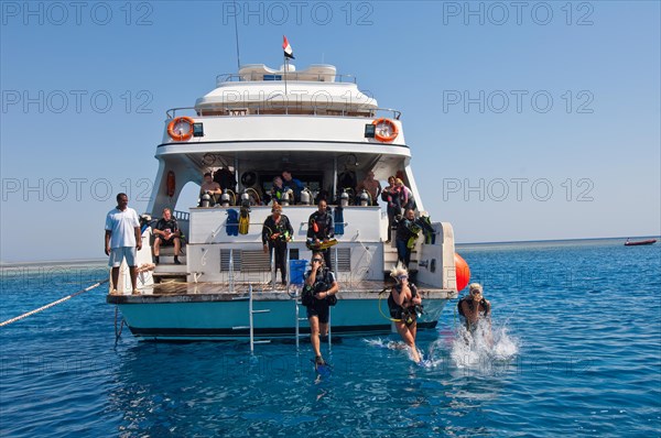 Divers make jump from dive platform of dive boat into water Sea