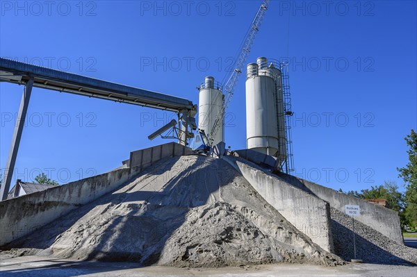 Steel silos and shovel crane with gravel piles and conveyor belt