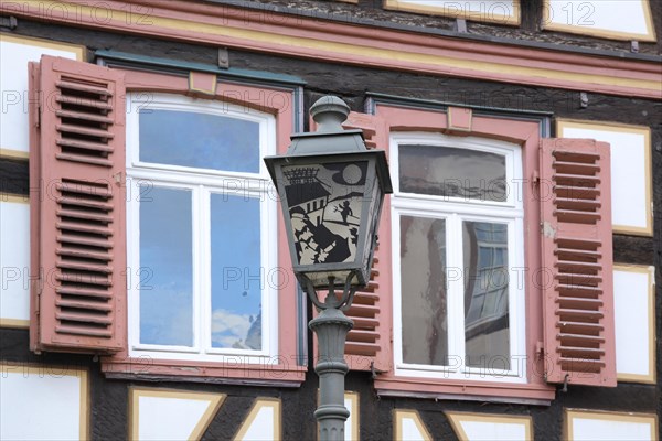 Half-timbered house with window shutter and lantern with historical motif