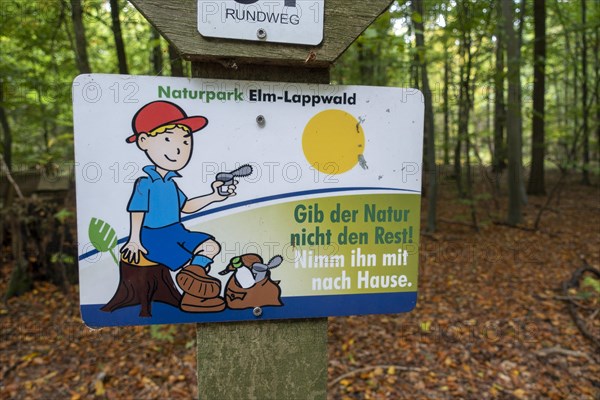 Sign with the inscription Don't give nature the rest! Take it home with you. under hiking signs in the autumnal forest