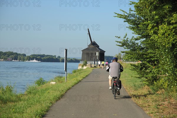 Historical wine loading crane built in 1745 and landmark on the banks of the Rhine with cycle path and cyclist from behind