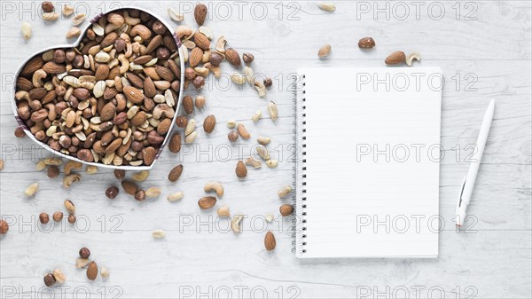 Blank notepad pen with dryfruits heart shape wooden desk