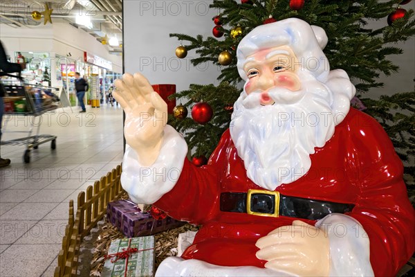 Father Christmas waving to passers-by with shopping trolley