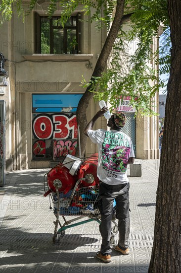 Man collects small metal in shopping trolley
