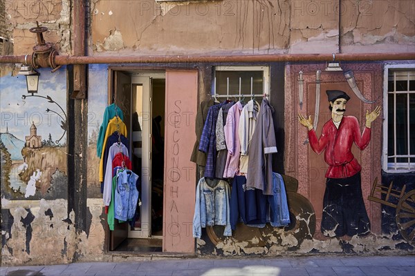 Clothes shop and graffito on the house wall